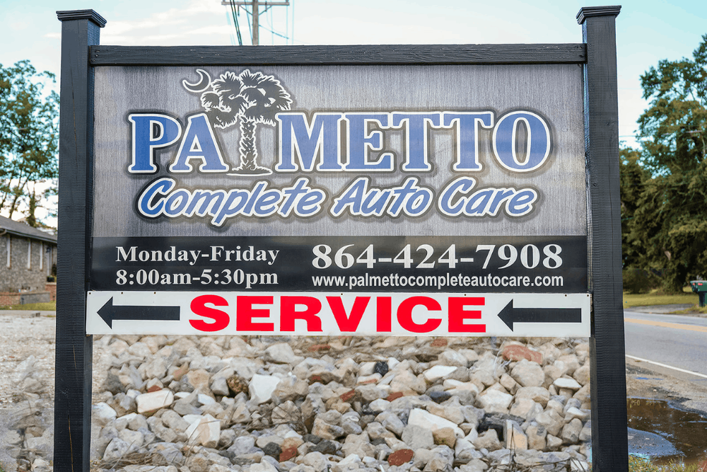 Auto repair and maintenance in Piedmont, SC by Palmetto Complete Auto Care. Image of the roadside shop sign displaying business name, service direction, hours, and contact information, emphasizing trusted local automotive care and easy service access.