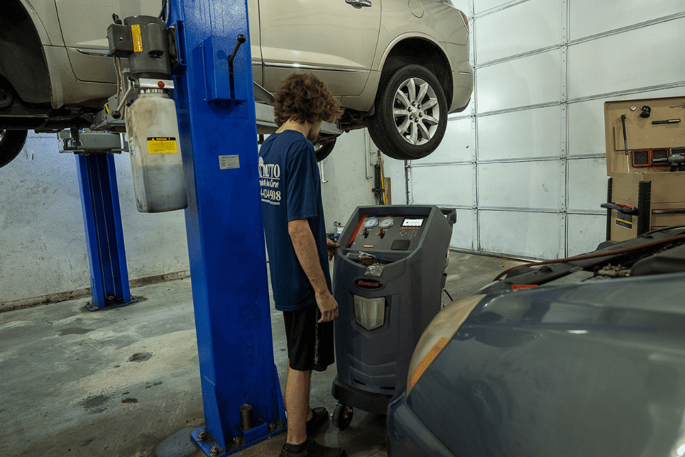 Summer Car Care inspection at Palmetto Complete Auto Care in Piedmont, SC. A mechanic inspecting the underside of a car during routine maintenance